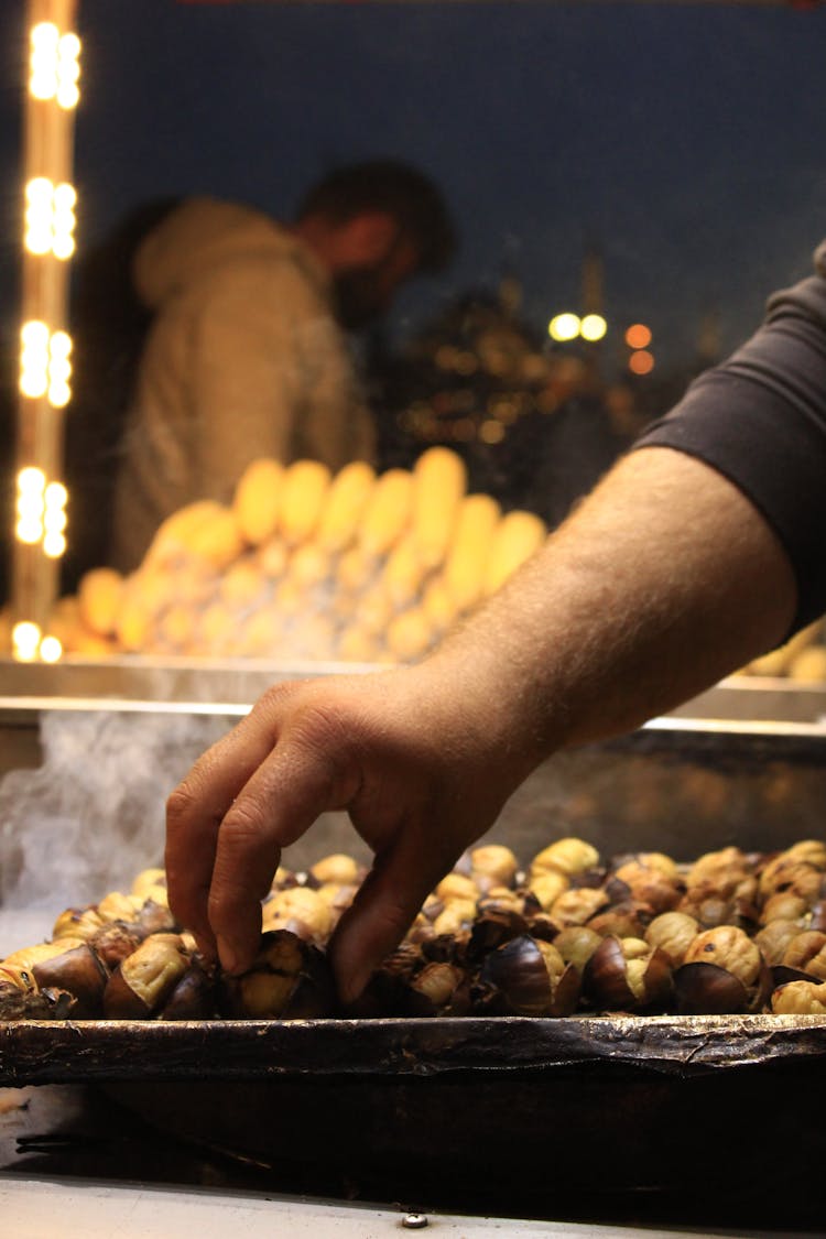 A Hand Picking Chestnuts On The Tray