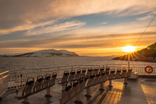 Stunning sunset view over the ocean from a ferry in Nordland, Norway, with empty seats and scenic horizons.