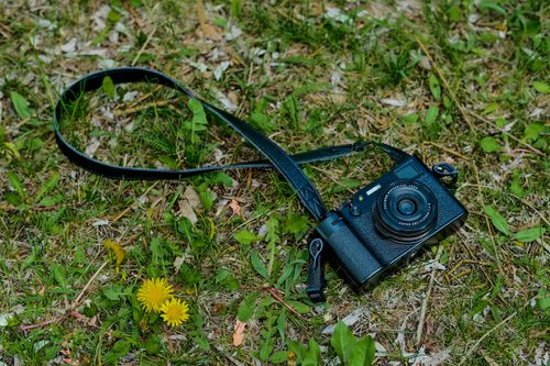 Free A close-up outdoor shot of a black camera resting on green grass, perfect for photography themes. Stock Photo