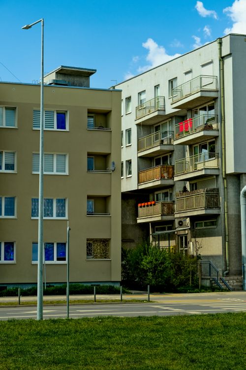 Free City apartment buildings with balconies, featuring a street lamp and lush green grass in the foreground. Stock Photo