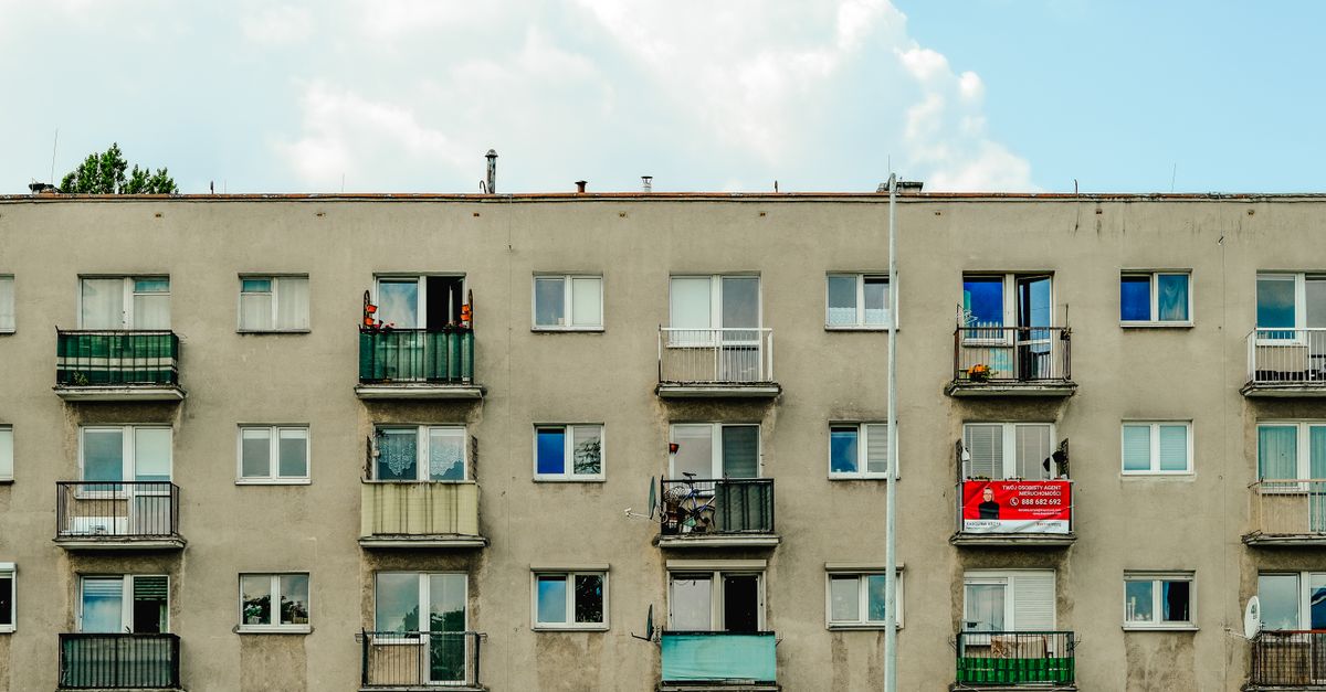 Facade of an urban apartment building with multiple balconies under blue sky.