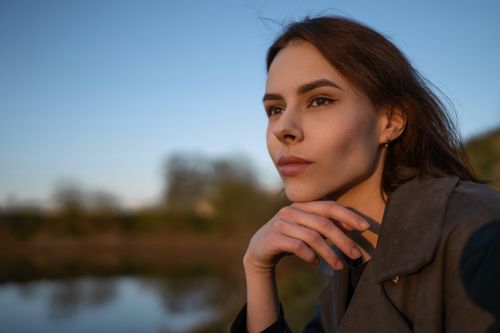 Free A contemplative woman gazes thoughtfully outdoors during sunset. Stock Photo