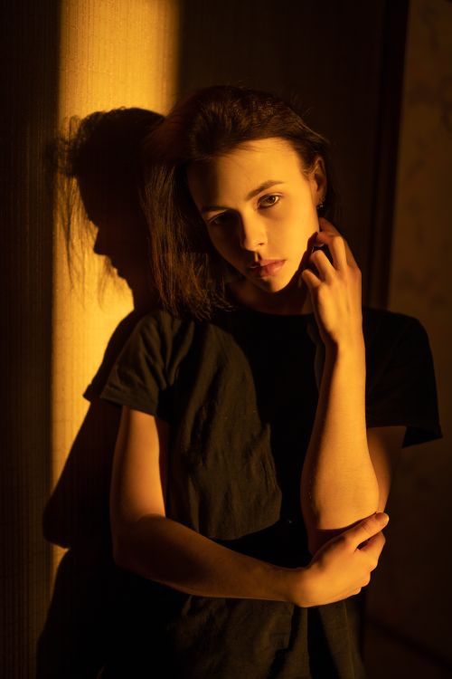 Free A woman poses thoughtfully in warm golden hour light, creating a moody and intimate atmosphere. Stock Photo