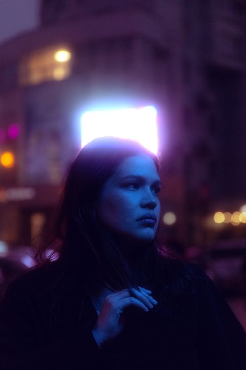 Free Portrait of a young woman illuminated by urban neon lights, capturing the essence of city nightlife. Stock Photo