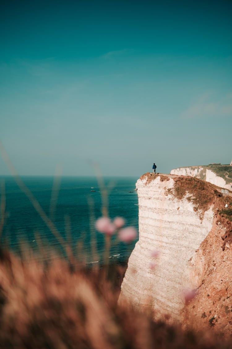 Person Standing On Edge Of Cliff Near Sea