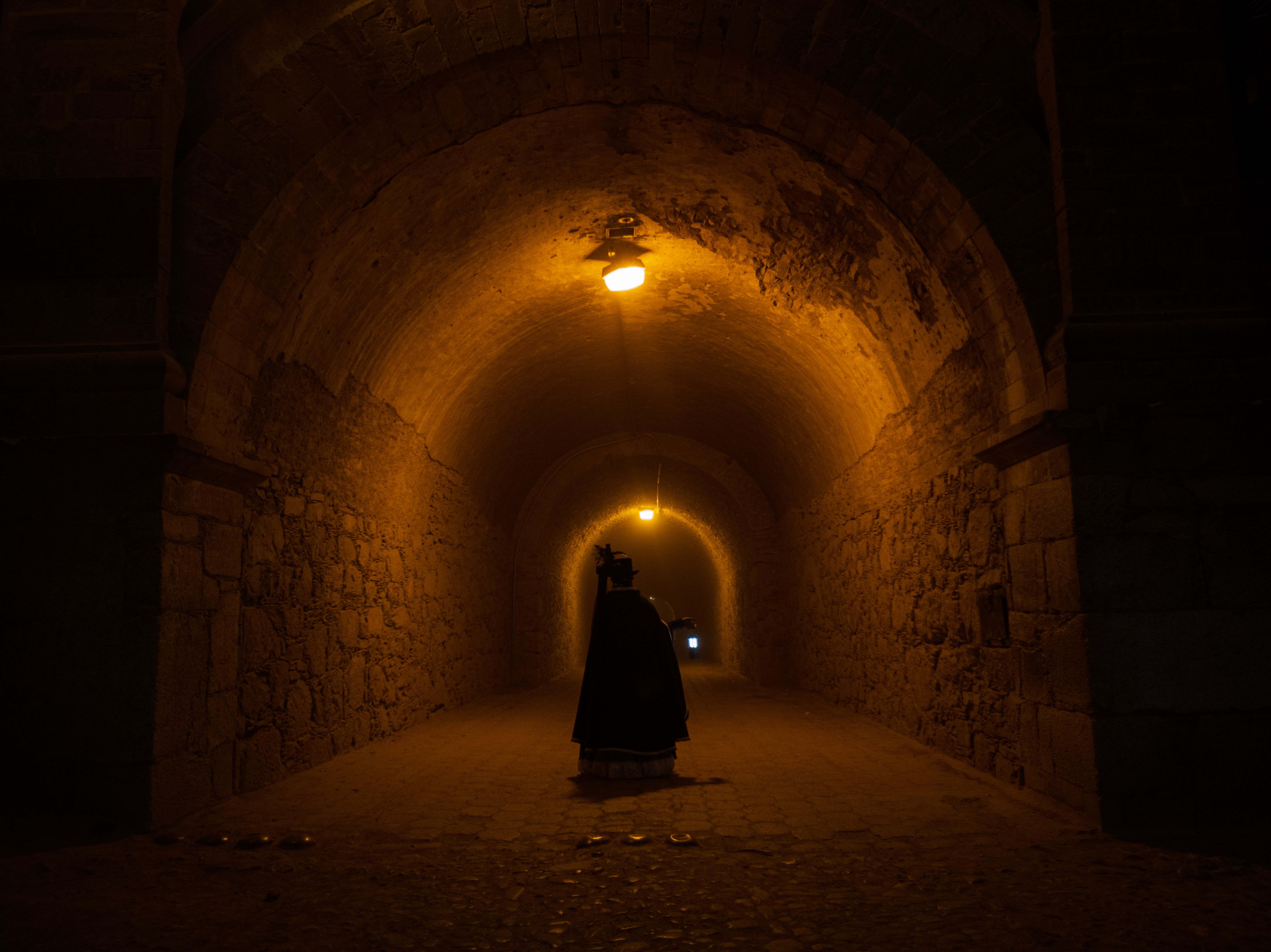 A dramatic castle interior with contestants in hooded cloaks whispering in a dark room