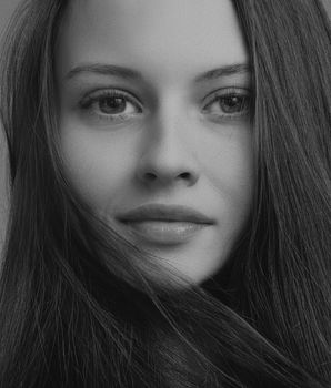 Close-up black and white portrait capturing a woman's expressive eyes and flowing hair.
