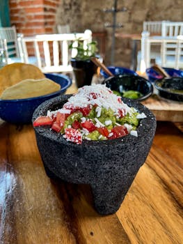 Authentic guacamole served in a molcajete with cheese and tomatoes, Mexico City.