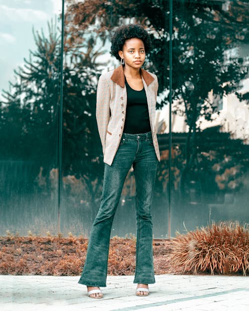 Woman in Brown Blazer Standing Beside a Glass Window