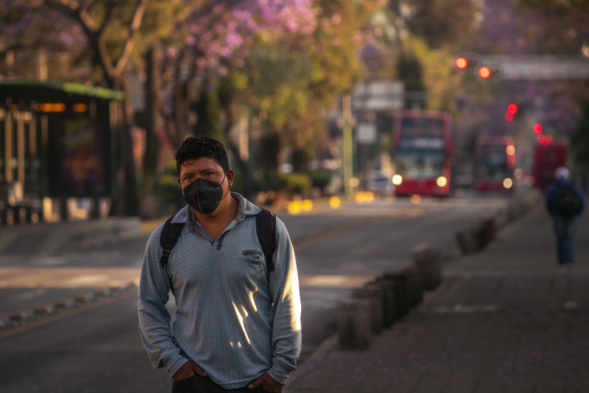 Man in face mask walking on a quiet street in Mexico City, showcasing urban life during pandemic times.