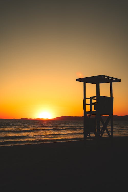 Silhouette of Lifeguard Tower on Beach during Sunset