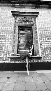 Ballet dancer performing a pose on tiptoe against a decorative wall, showcasing elegance and balance.
