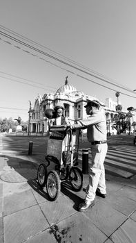 A street vendor with a cart stands near a historic building, captured in black and white.