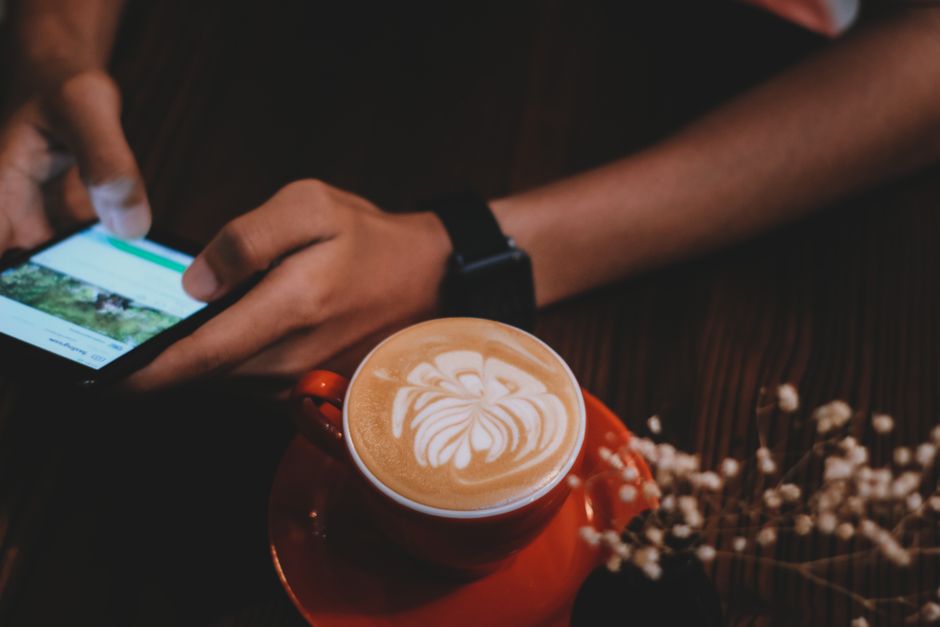 Personne qui lit sur son smartphone à côté d'un café, dans une ambiance calme