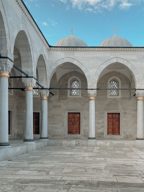 Free Elegant courtyard with marble columns and domes showcasing Islamic architecture in daylight. Stock Photo