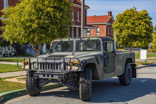 Free Camouflage military Hummer vehicle parked along a suburban street on a sunny day. Stock Photo