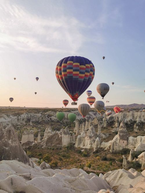 Free Colorful hot air balloons floating over Cappadocia's iconic rocky landscape. Stock Photo