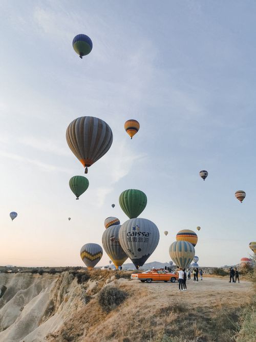 Free Hot air balloons gracefully floating over the rocky landscapes of Cappadocia under a clear morning sky. Stock Photo