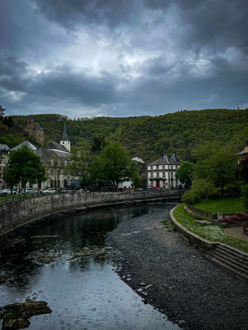 Free Scenic view of a riverside town with lush greenery and historic architecture under a cloudy sky. Stock Photo