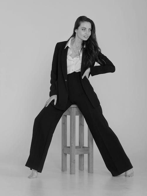 A Woman in Black Blazer and Black Pants Sitting on Wooden Chair