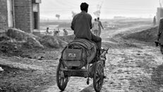 Man in Black Jacket Sitting on Black Wheelchair on Gray Sand