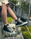 Woman in Black and White Converse All Star High Tops Sitting on Gray Rock