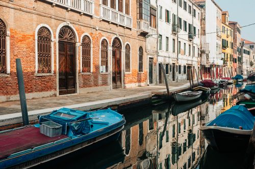 Free Serene canal scene showcasing colorful boats and historic buildings with reflections in Venice, Italy. Stock Photo