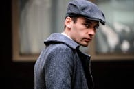 一位穿着灰色外套、戴着帽子的男子肖像，在户外显得很时尚