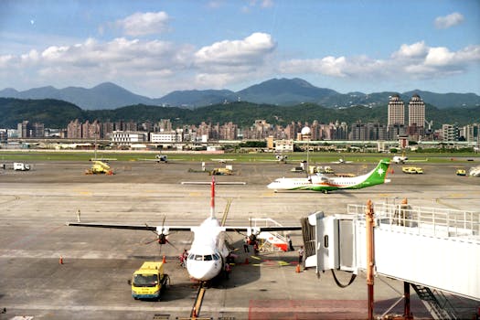 Aerial view of planes and tarmac at Songshan Airport in Taipei, Taiwan, with city skyline in background.