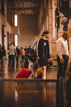 A young traveler with a red suitcase navigating a busy terminal.