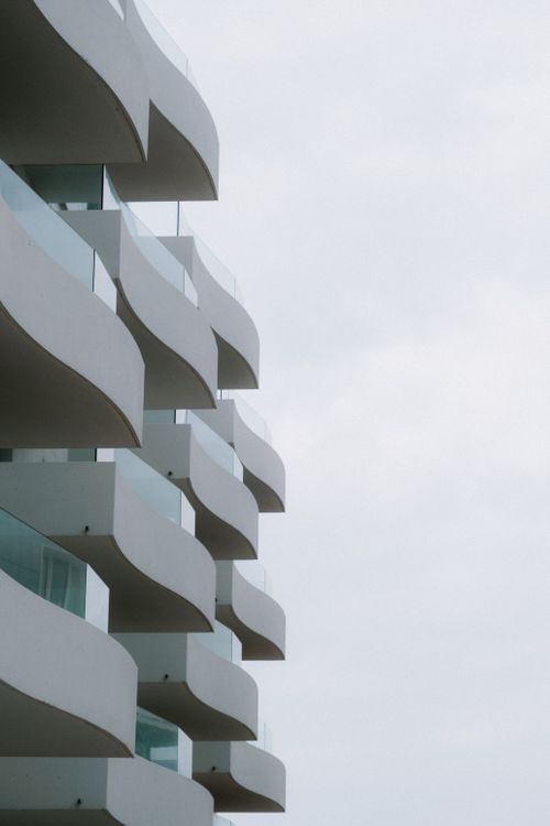 Free Modern building with unique balcony design against a minimalist sky. Stock Photo