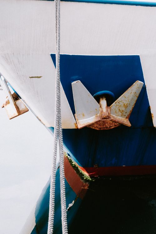 Free Detailed view of a rusty anchor on a boat reflecting in calm water. Close-up shot. Stock Photo