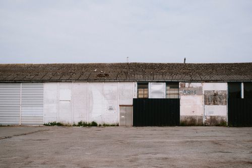 Free Rustic industrial warehouse with weathered facade and empty surroundings. Stock Photo