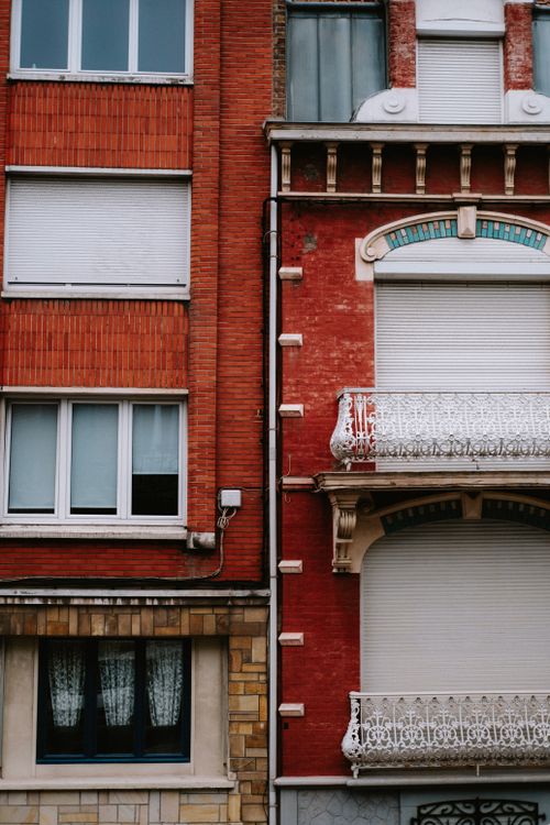 Free Vertical shot of apartment facades showcasing detailed brickwork and ornate balconies. Stock Photo