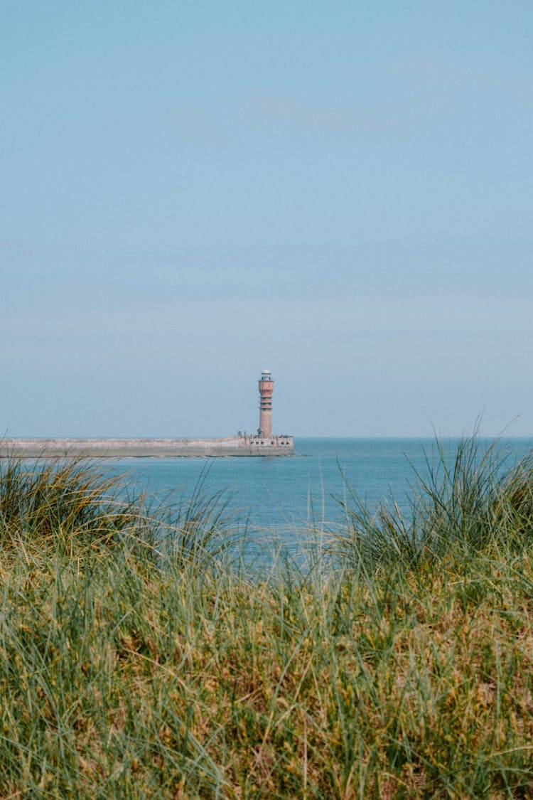 Distant View Of Lighthouse Standing On Pier End