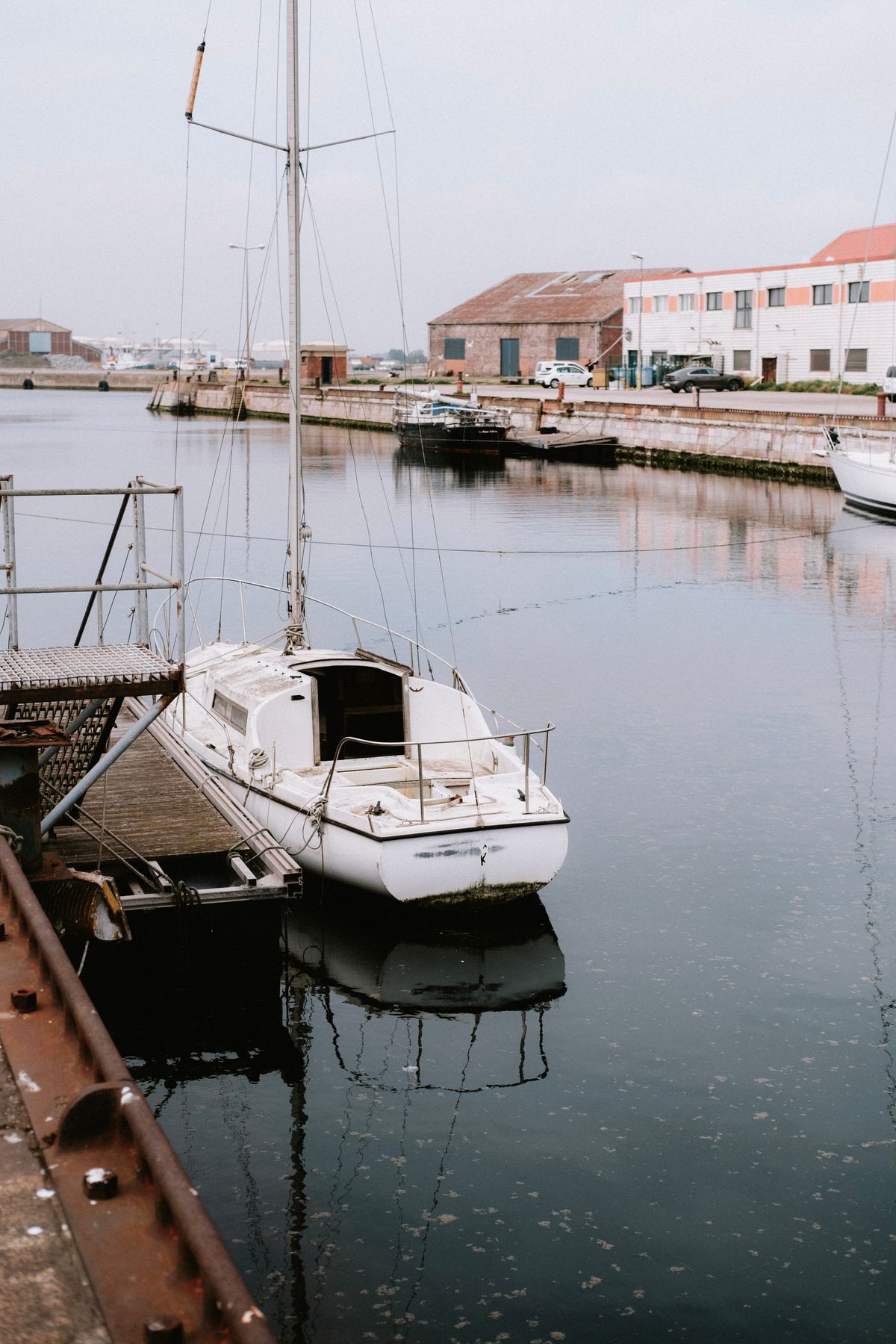 A sailboat moored beside a pier in soft daylight