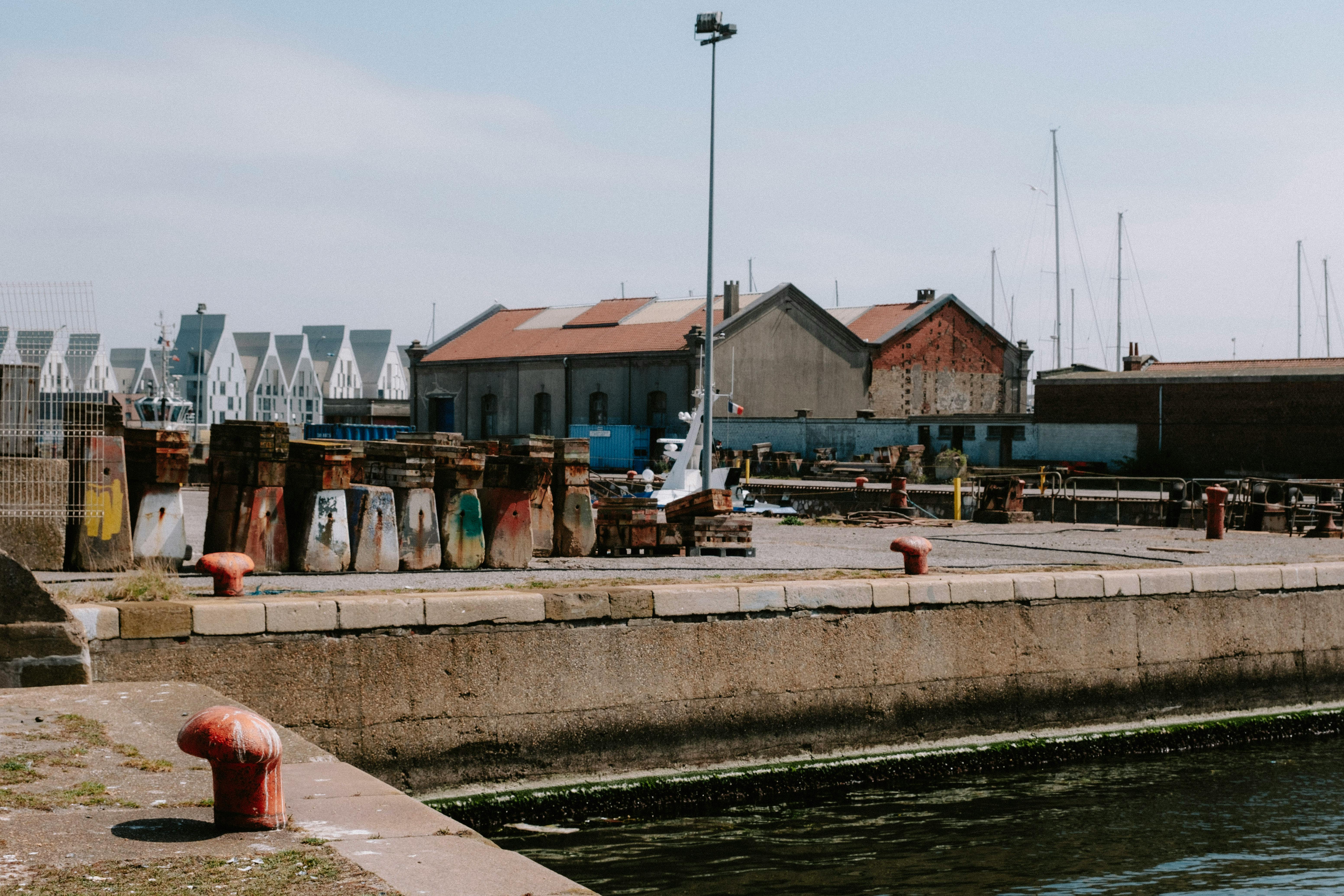 Explore an industrial harbor scene with aged buildings and colorful quay structures under a clear sky.