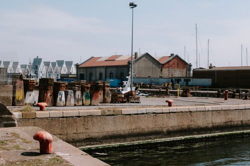Free Explore an industrial harbor scene with aged buildings and colorful quay structures under a clear sky. Stock Photo