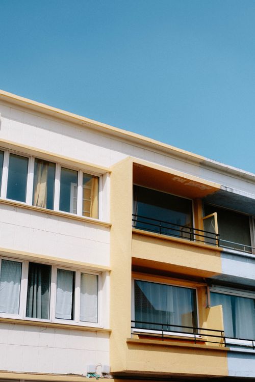 Free Urban residential building with colorful facades and balconies under a clear blue sky. Stock Photo