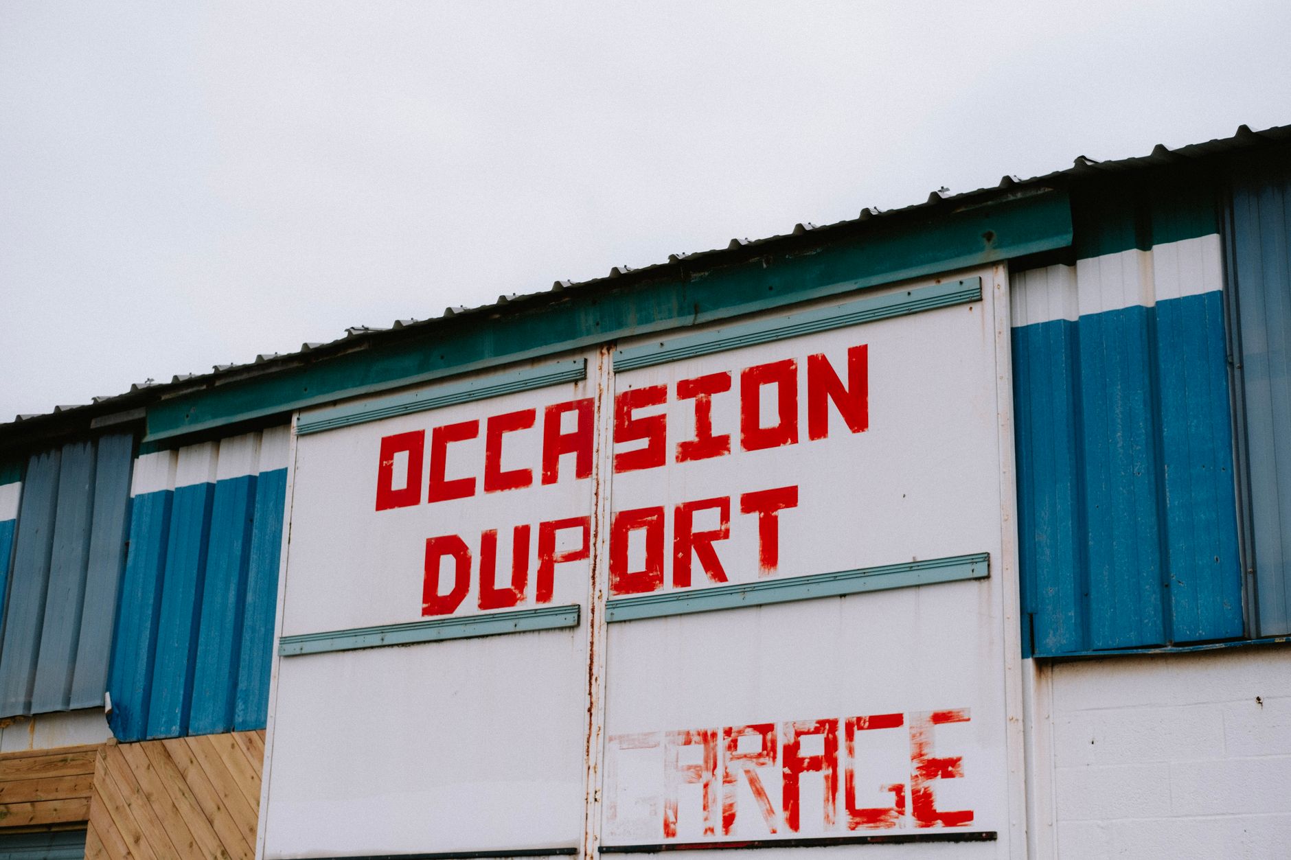 Blue and white industrial building facade with red signage in Dunkerque, France.