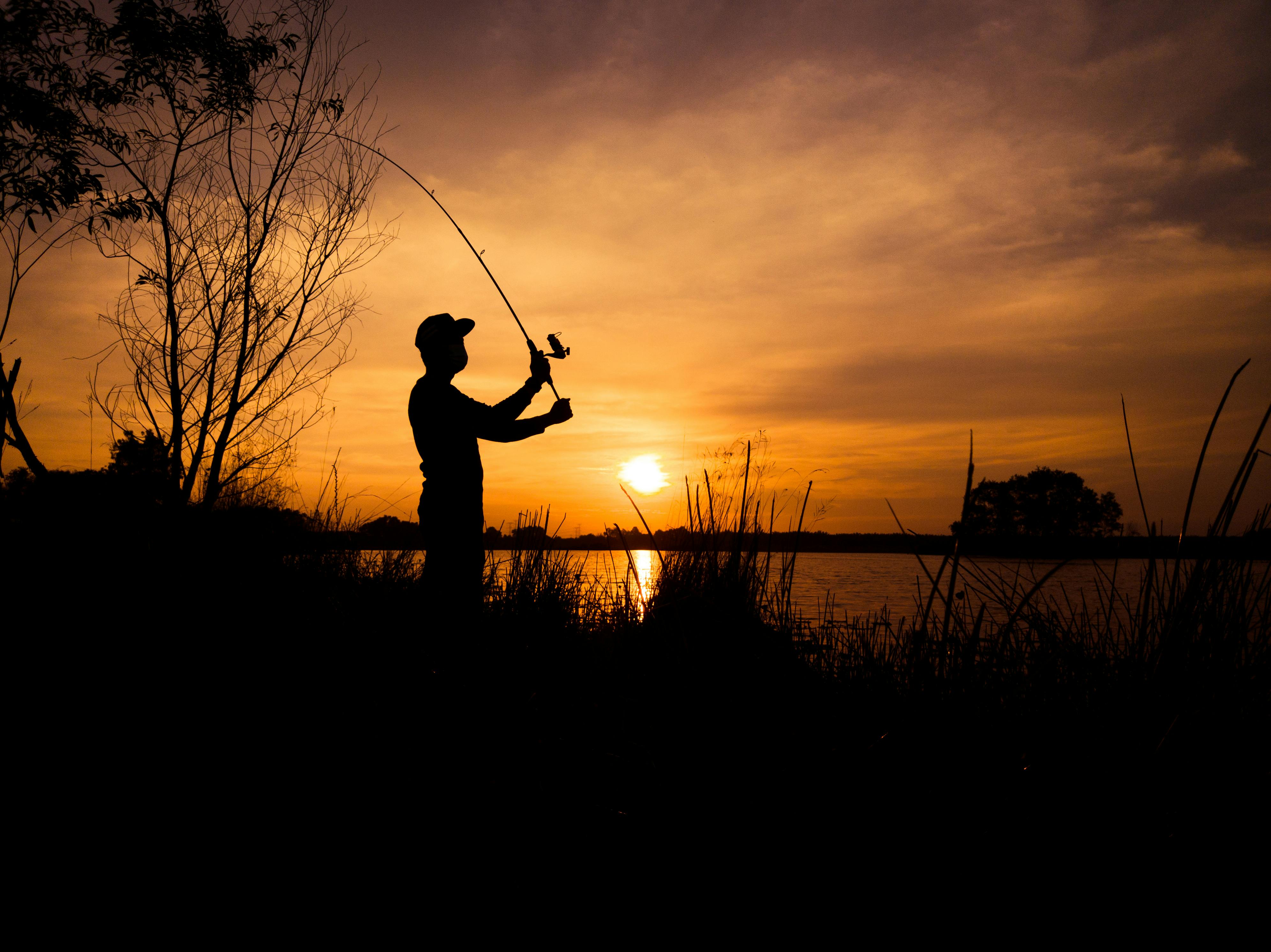 Silhouette of Man Holding Fishing Rod During Sunset · Free Stock Photo