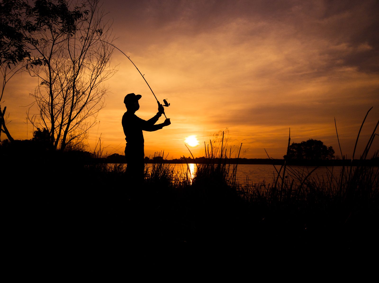 Pescador al atardecer en la orilla de un río
