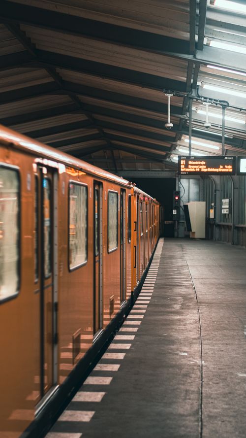 Free An orange train at a quiet indoor station with industrial design elements. Stock Photo