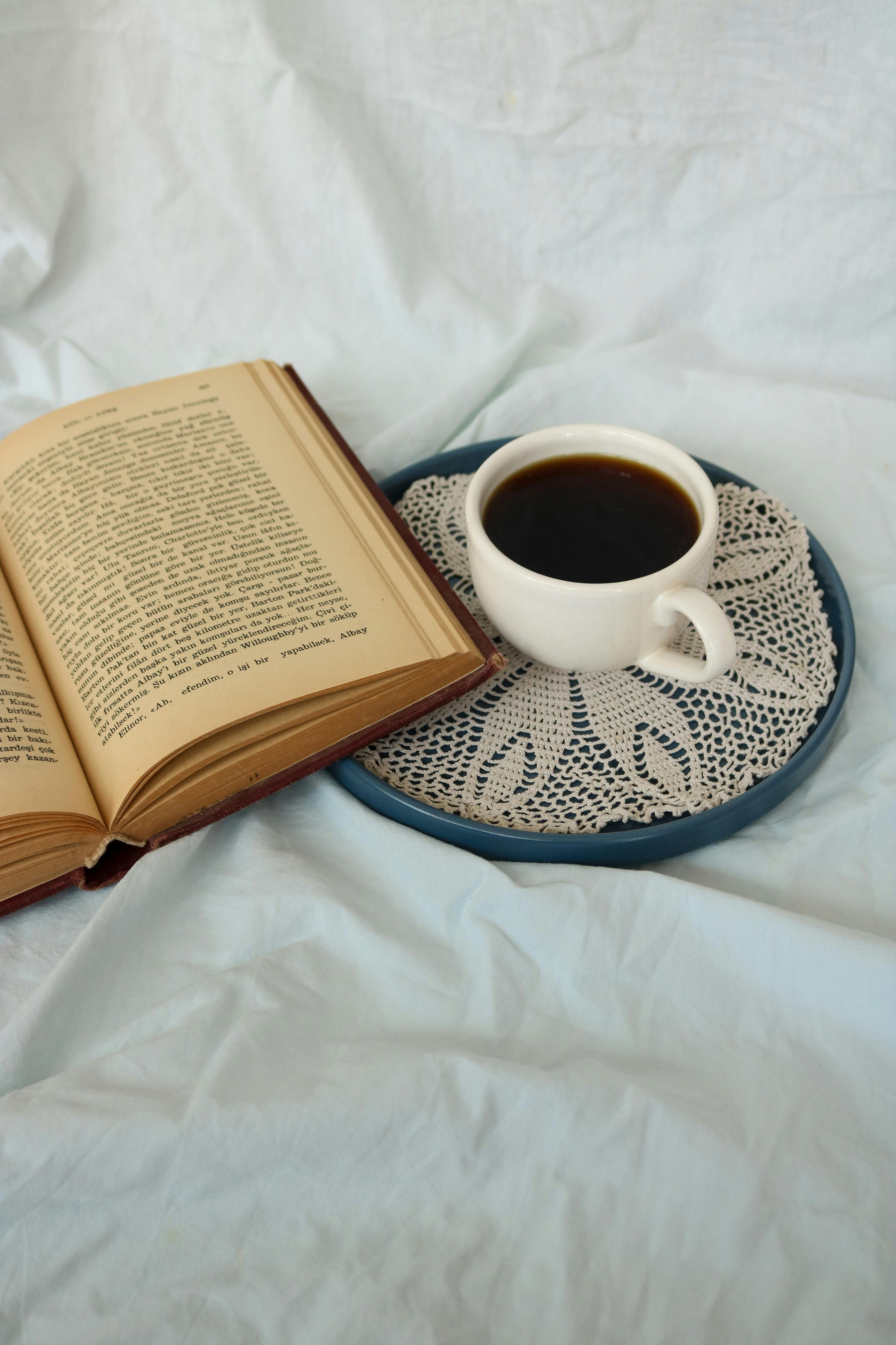 A warm scene with a cozy open book and a cup of coffee on a doily.