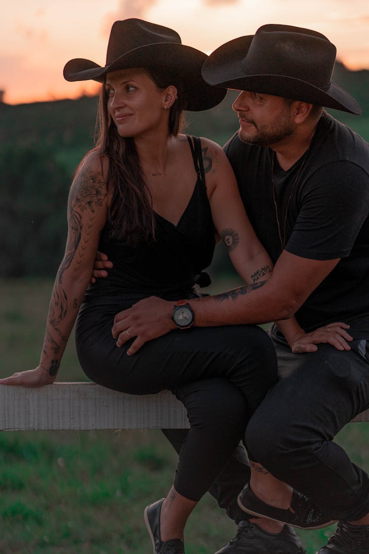 Couple Sitting On Wooden Fence