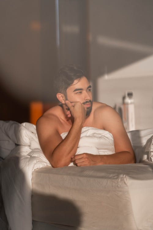 Shirtless Man Lying on Bed