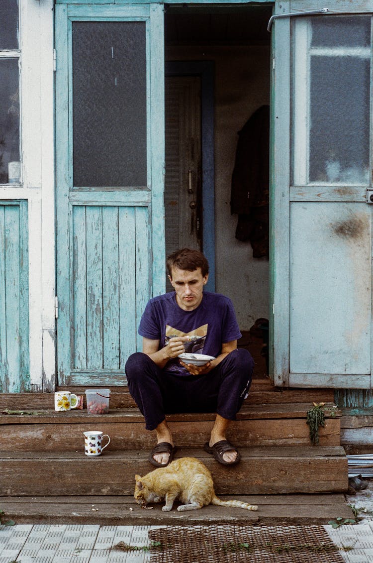 Man And Cat Eating On Stairs