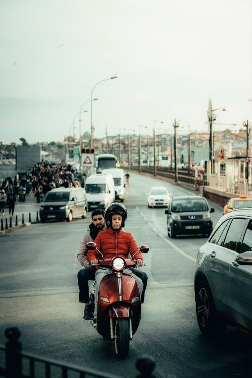 Free Scooter riders navigate through traffic on a bustling urban road. Stock Photo