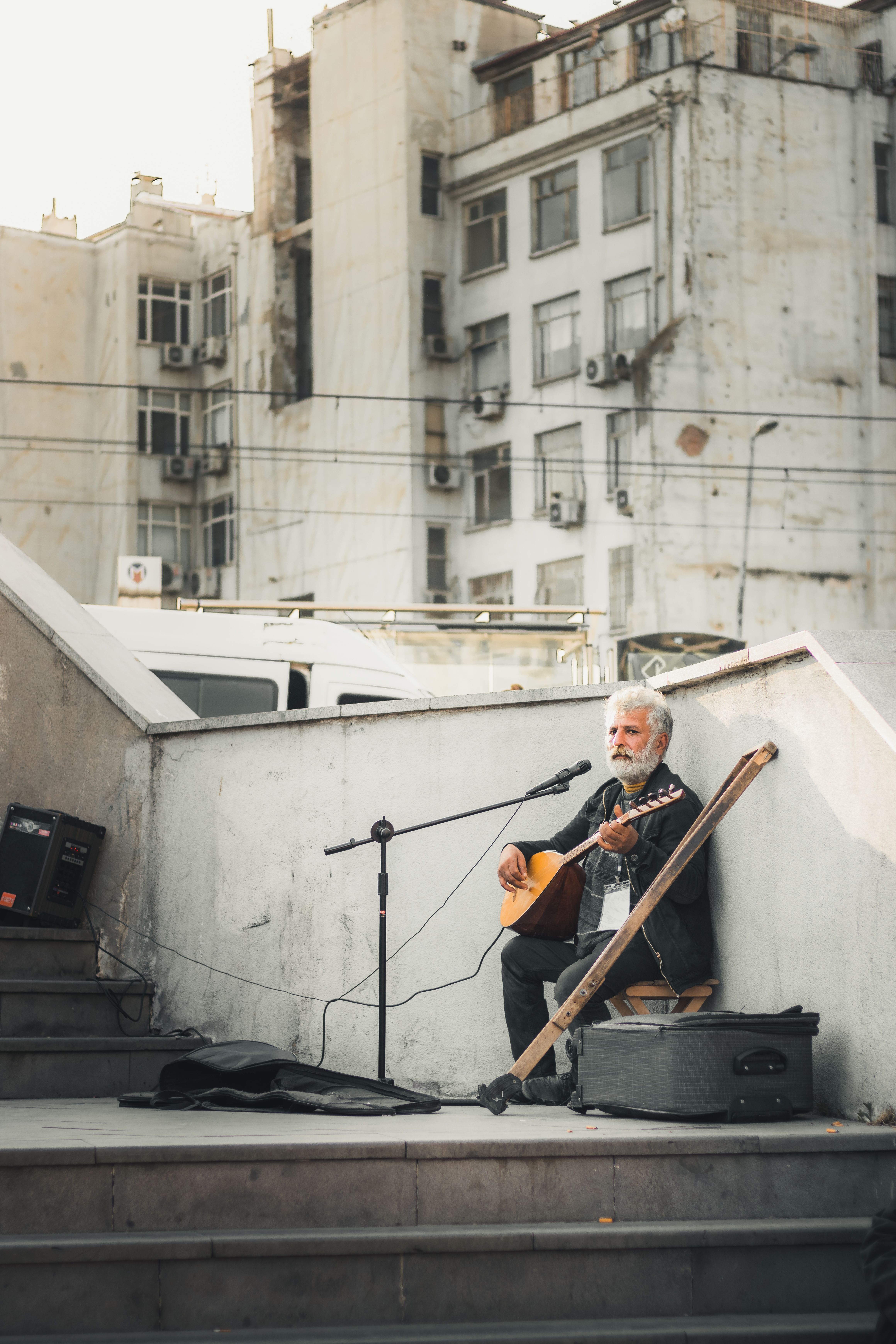 Senior musician performs on a city street with a guitar, adding a cultural vibe to the urban landscape.