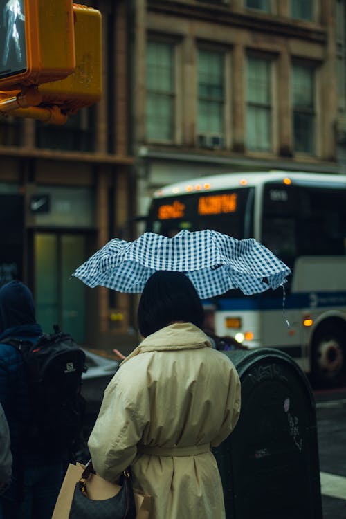 Free A Person in Beige Coat Holding Umbrella Walking on Street Stock Photo